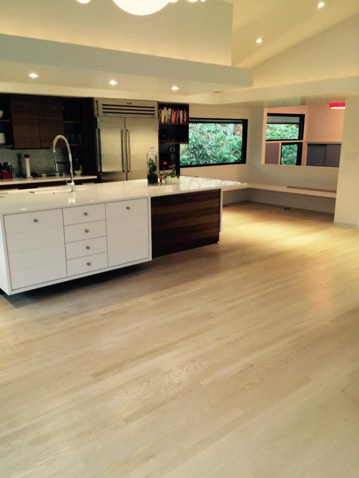 Open concept kitchen - large l-shaped light wood floor open concept kitchen idea in New York with an integrated sink, flat-panel cabinets, white cabinets, blue backsplash, glass sheet backsplash, stainless steel appliances and an island