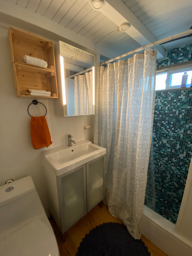 Источник вдохновения для домашнего уюта: маленькая ванная комната в стиле кантри с стеклянными фасадами, белыми фасадами, угловым душем, унитазом-моноблоком, разноцветной плиткой, белыми стенами, светлым паркетным полом, душевой кабиной, накладной раковиной, столешницей из ламината, коричневым полом, шторкой для ванной, белой столешницей, тумбой под одну раковину, напольной тумбой, потолком из вагонки и стенами из вагонки для на участке и в саду