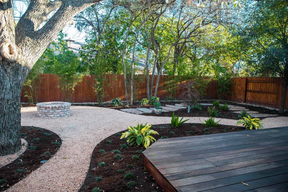 This is an example of a small asian backyard shaded garden for spring in Austin with a fire feature and gravel.