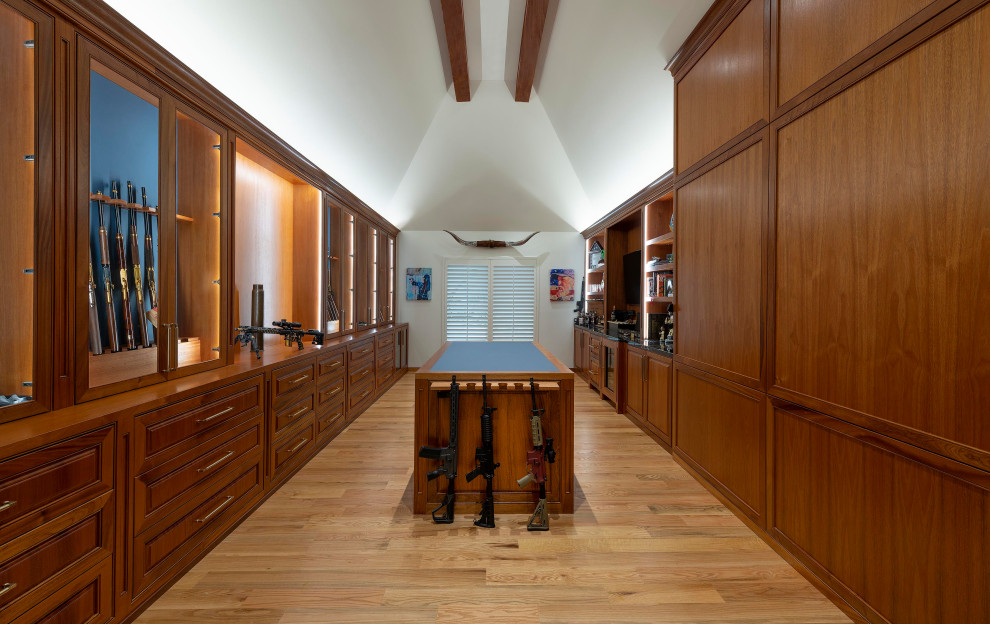 This is an example of an expansive traditional gender-neutral walk-in wardrobe in Dallas with raised-panel cabinets, dark wood cabinets, light hardwood floors, brown floor and vaulted.