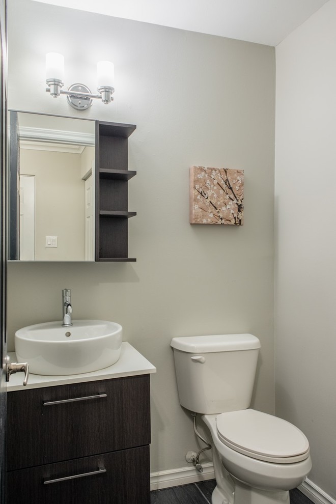This is an example of a small contemporary powder room in Toronto with flat-panel cabinets, brown cabinets, a one-piece toilet, grey walls, porcelain floors, a vessel sink and grey floor.