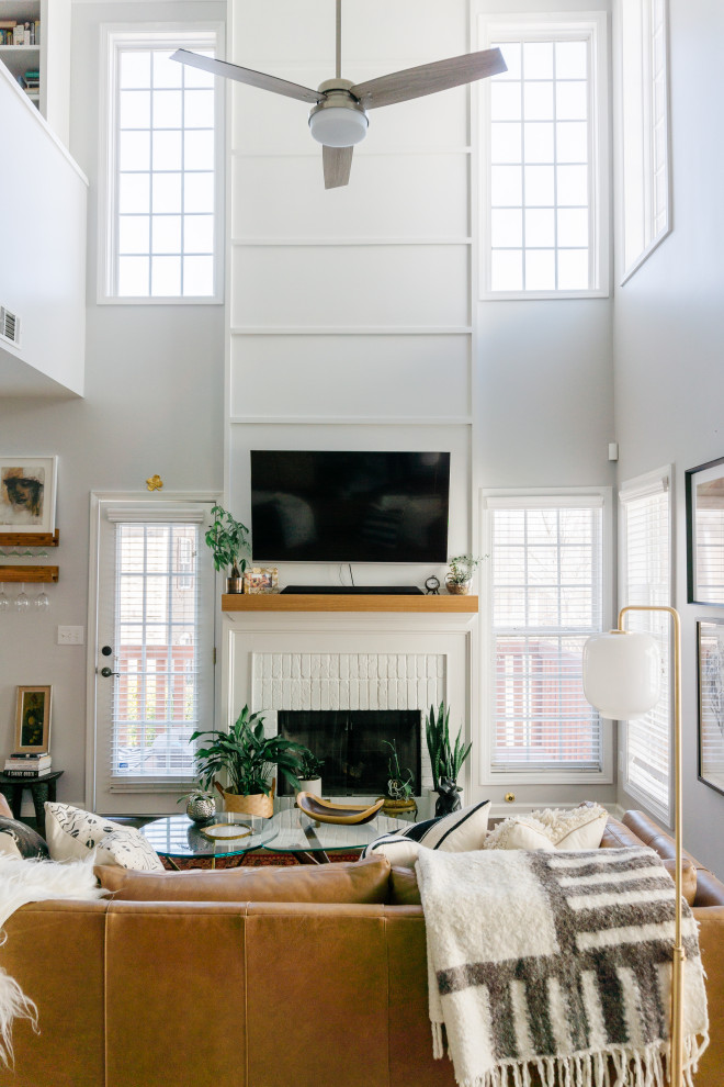 Design ideas for a small eclectic loft-style living room in Atlanta with white walls, medium hardwood floors, a standard fireplace, a brick fireplace surround, a wall-mounted tv, brown floor and panelled walls.
