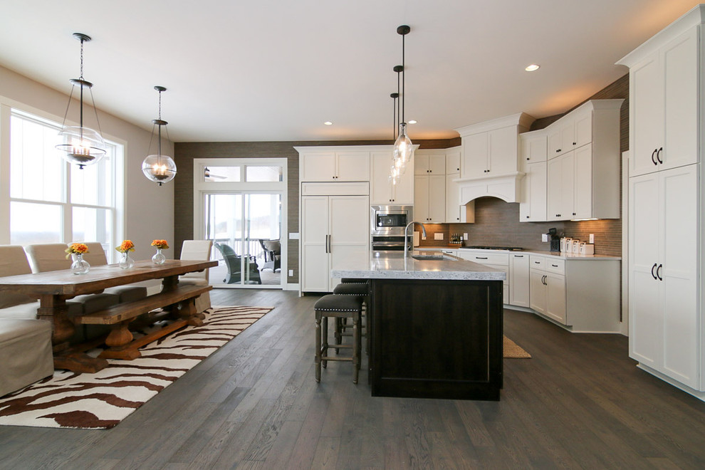 Eat-in kitchen - large transitional u-shaped medium tone wood floor and brown floor eat-in kitchen idea with a drop-in sink, recessed-panel cabinets, white cabinets, marble countertops, beige backsplash, stone tile backsplash, stainless steel appliances and an island