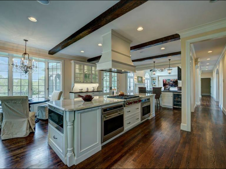 Inspiration for a large transitional u-shaped dark wood floor and brown floor open concept kitchen remodel with an undermount sink, beaded inset cabinets, white cabinets, quartzite countertops, white backsplash, stainless steel appliances, an island and white countertops