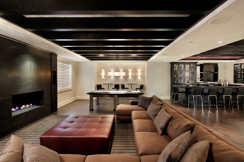 Photo of a large contemporary basement in Chicago with white walls, dark hardwood floors, a ribbon fireplace, a metal fireplace surround and brown floor.