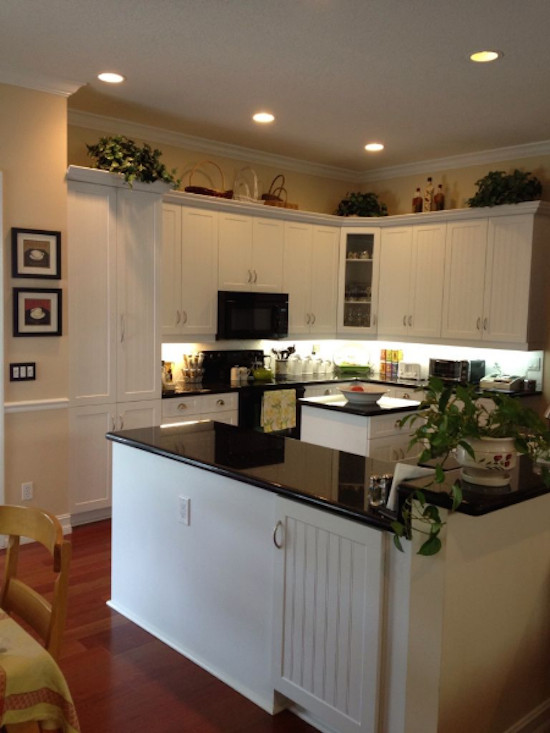 Eat-in kitchen - mid-sized u-shaped medium tone wood floor eat-in kitchen idea in Miami with a double-bowl sink, shaker cabinets, white cabinets, white backsplash, black appliances and an island