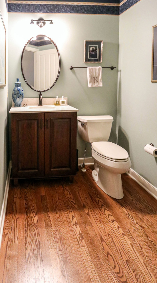 Small powder room in Cleveland with raised-panel cabinets, dark wood cabinets, a two-piece toilet, green walls, dark hardwood floors, an undermount sink, engineered quartz benchtops, beige benchtops and a freestanding vanity.