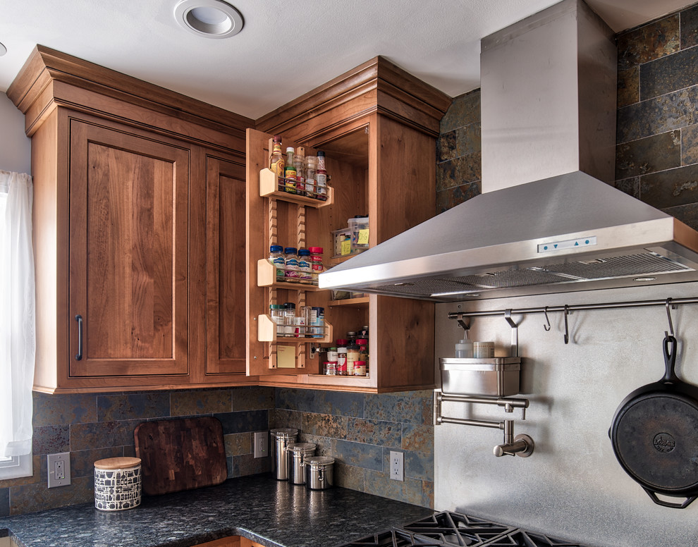 Mid-sized industrial l-shaped eat-in kitchen in New York with an undermount sink, beaded inset cabinets, medium wood cabinets, granite benchtops, grey splashback, slate splashback, stainless steel appliances, ceramic floors, with island and brown floor.