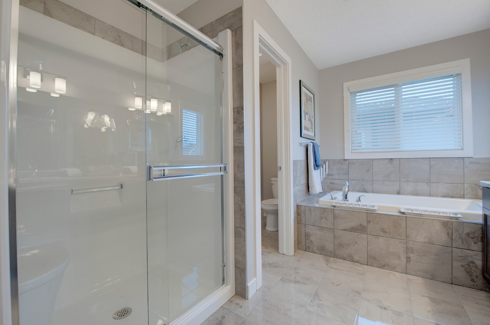 Drop-in bathtub - mid-sized transitional master gray tile and porcelain tile porcelain tile drop-in bathtub idea in Edmonton with shaker cabinets, medium tone wood cabinets, a one-piece toilet, gray walls, a drop-in sink and laminate countertops