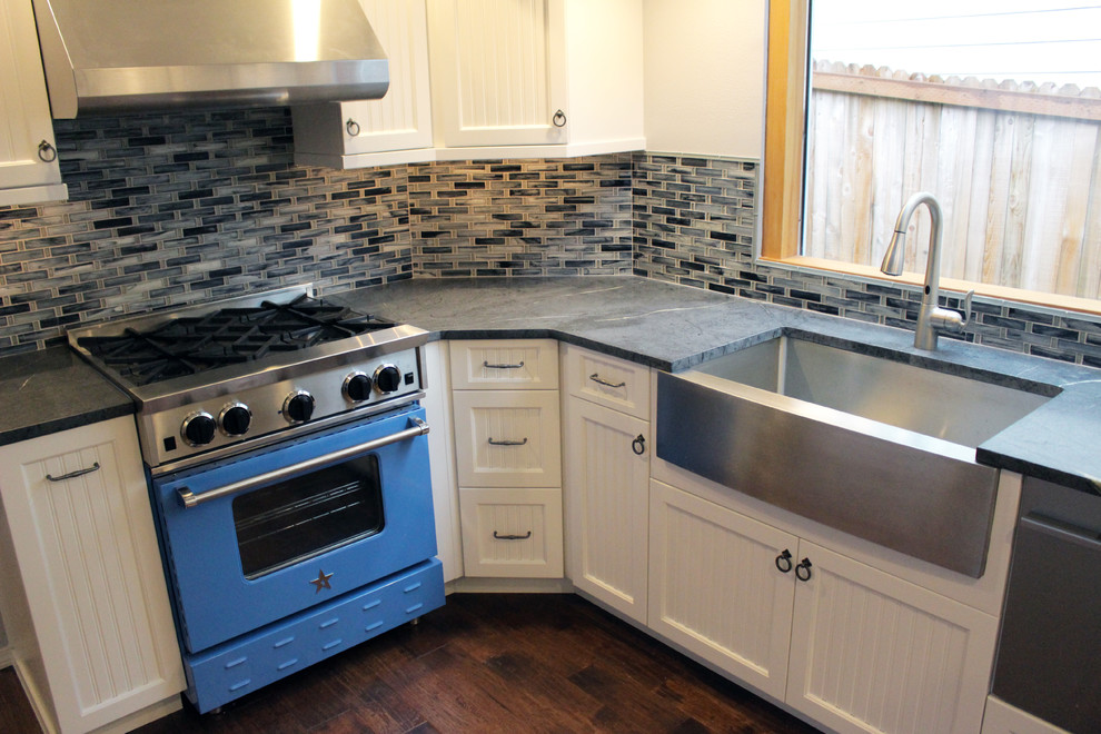 Large arts and crafts u-shaped kitchen in Seattle with a farmhouse sink, white cabinets, stainless steel appliances, soapstone benchtops, blue splashback, mosaic tile splashback, dark hardwood floors and with island.