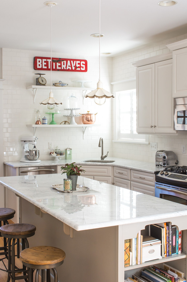 Photo of a mid-sized country eat-in kitchen in Denver with an undermount sink, raised-panel cabinets, white cabinets, marble benchtops, white splashback, subway tile splashback, stainless steel appliances and with island.