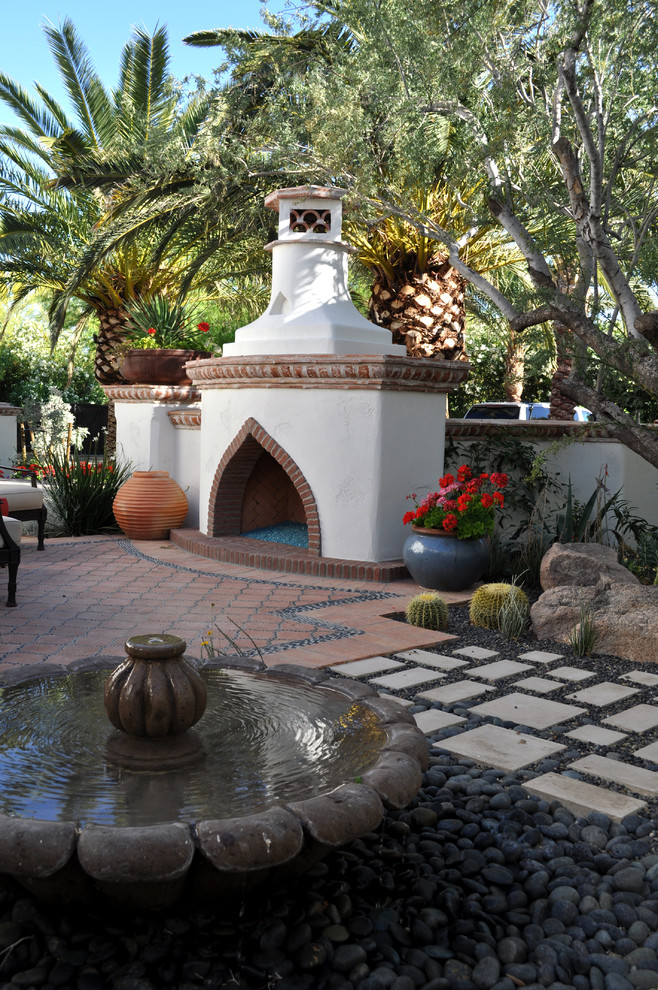 Photo of a mid-sized mediterranean courtyard patio in Phoenix with a fire feature, tile and no cover.