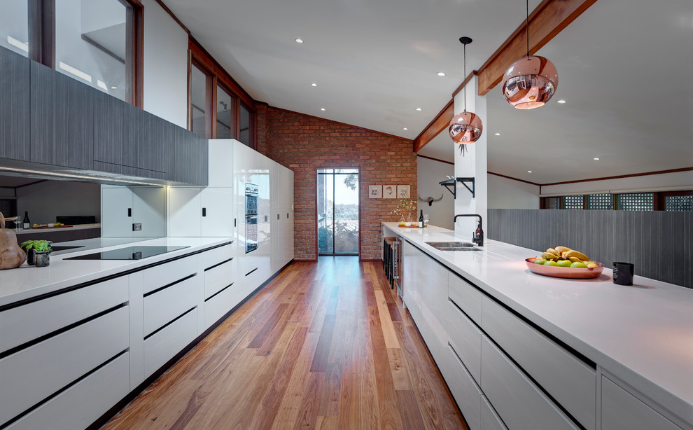 This is an example of a large contemporary galley kitchen in Other with a double-bowl sink, white cabinets, laminate benchtops, stainless steel appliances, medium hardwood floors, glass sheet splashback, flat-panel cabinets and with island.