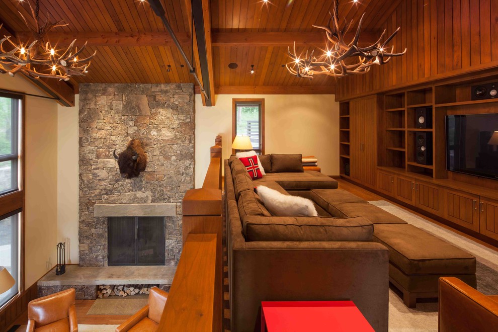 Photo of an expansive country loft-style living room in Portland with a wall-mounted tv, white walls, medium hardwood floors, a standard fireplace and a stone fireplace surround.