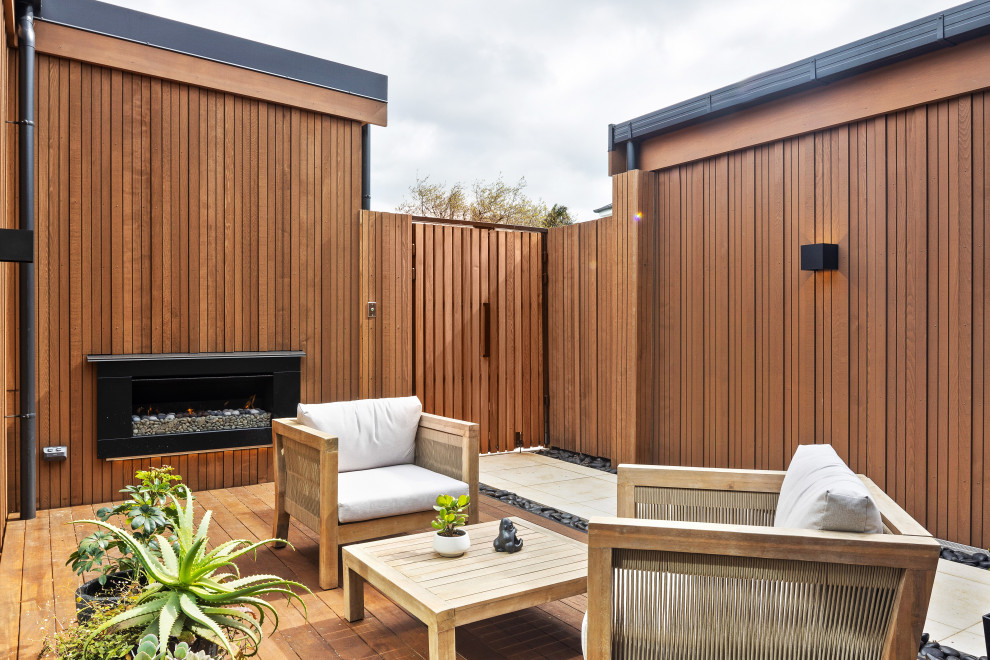 Design ideas for a medium sized contemporary courtyard patio in Auckland with a fireplace and an awning.