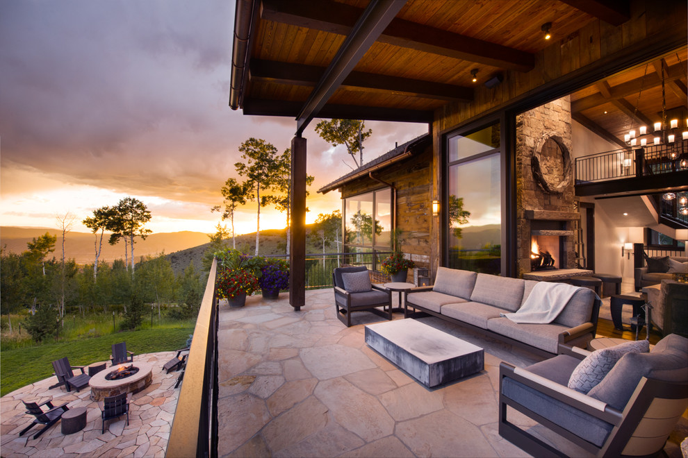 Inspiration for an expansive transitional backyard deck in Denver with a fire feature and a roof extension.