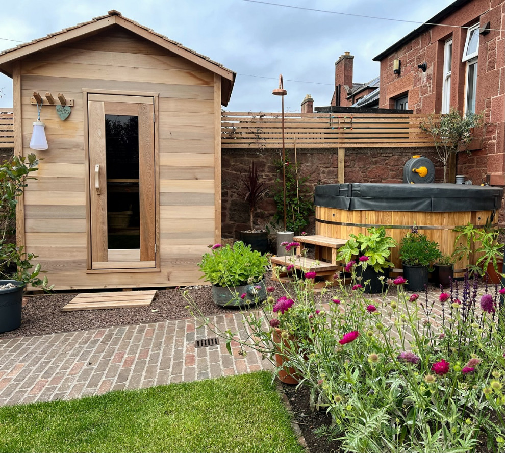Immagine di un piccolo giardino nordico esposto in pieno sole dietro casa in estate con pavimentazioni in mattoni e recinzione in legno