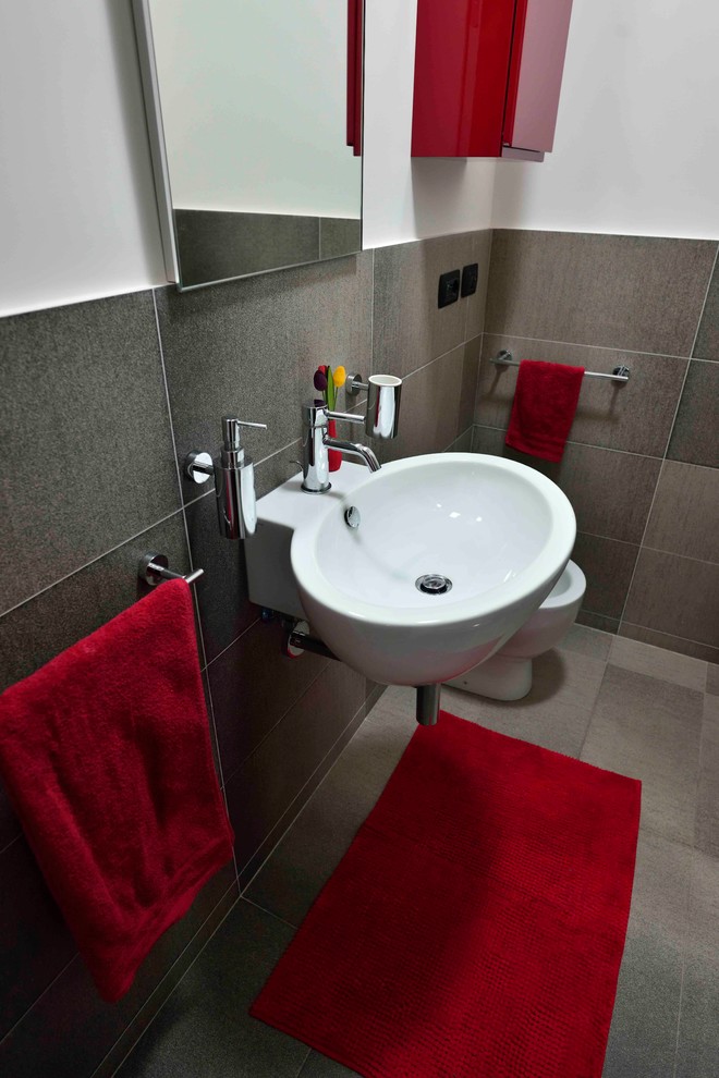 Design ideas for a small contemporary powder room in Rome with flat-panel cabinets, red cabinets, a two-piece toilet, gray tile, porcelain tile, white walls, porcelain floors, a wall-mount sink and grey floor.