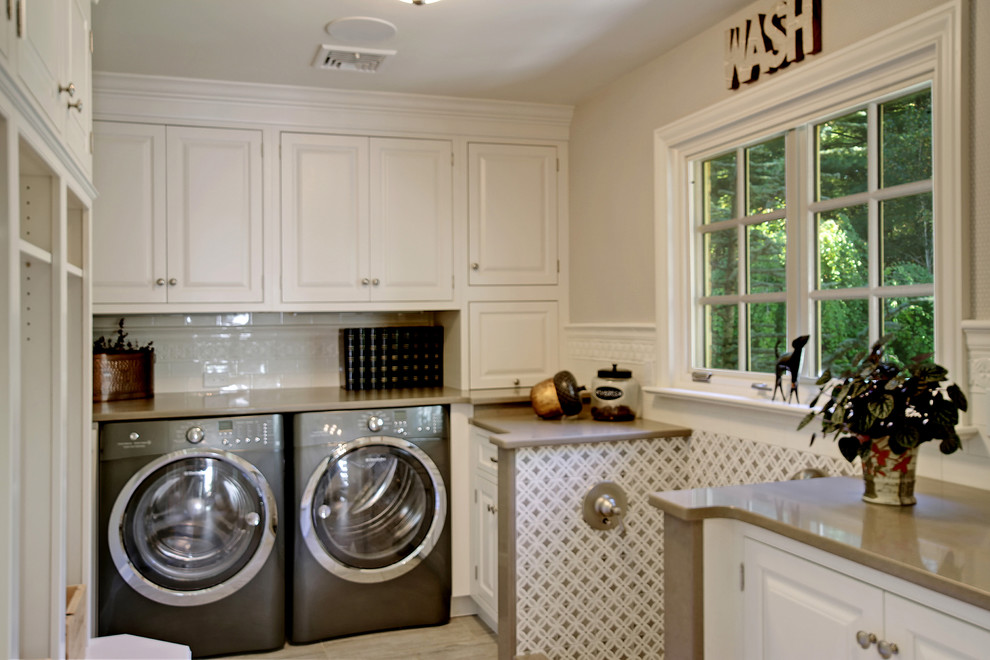 This is an example of a mid-sized transitional dedicated laundry room in New York with raised-panel cabinets, white cabinets, beige walls and a side-by-side washer and dryer.