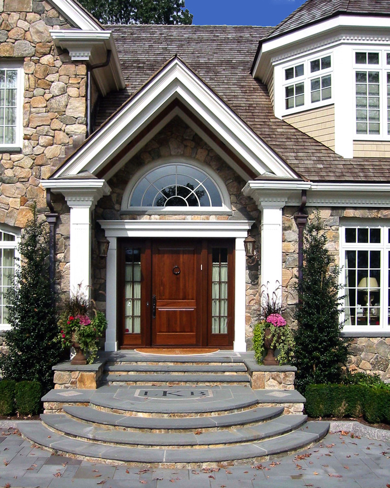 This is an example of a large traditional two-storey beige house exterior in Boston with stone veneer, a gable roof and a shingle roof.