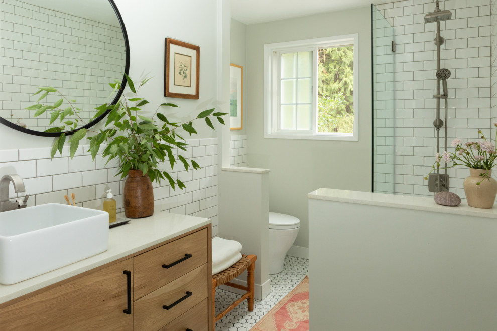 Пример оригинального дизайна: маленькая ванная комната в стиле ретро с плоскими фасадами, светлыми деревянными фасадами, ванной в нише, душем над ванной, унитазом-моноблоком, белой плиткой, керамической плиткой, серыми стенами, полом из керамогранита, настольной раковиной, столешницей из искусственного кварца, белым полом, душем с распашными дверями, белой столешницей, тумбой под одну раковину и напольной тумбой для на участке и в саду