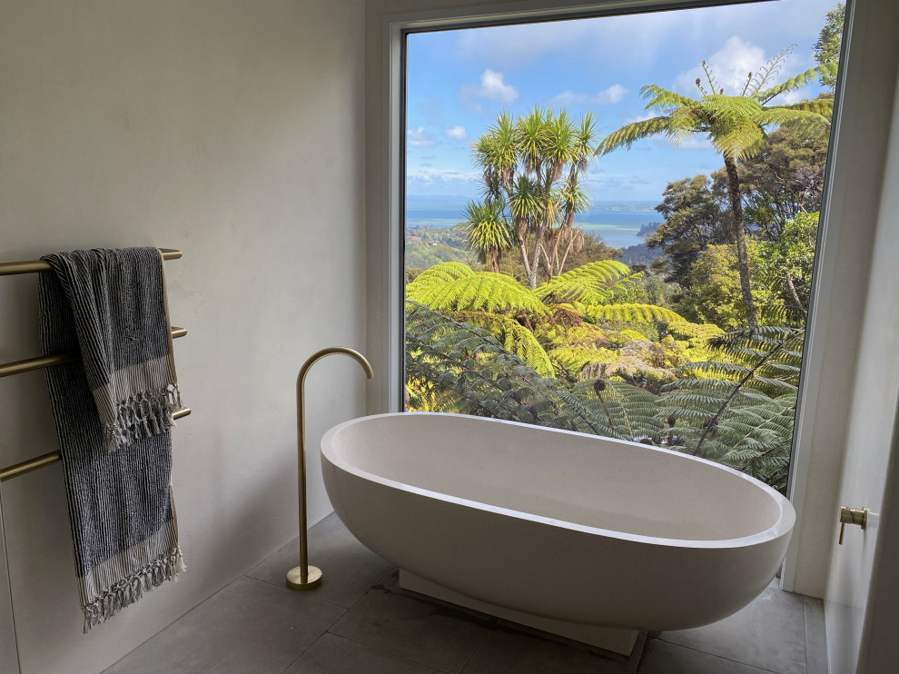 На фото: ванная комната среднего размера в современном стиле с отдельно стоящей ванной, открытым душем, каменной плиткой, серыми стенами, открытым душем и подвесной тумбой с