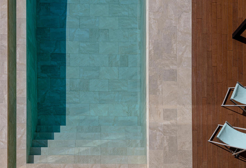 Diseño de piscina infinita minimalista grande rectangular en patio delantero con suelo de baldosas