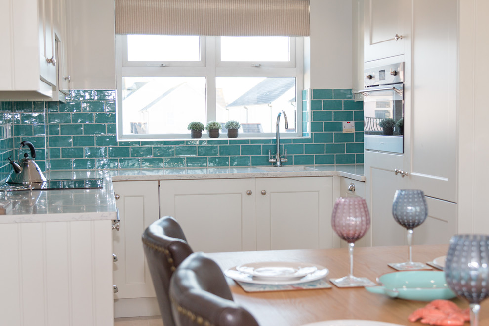 Photo of a small beach style u-shaped open plan kitchen in Other with an undermount sink, shaker cabinets, beige cabinets, marble benchtops, green splashback, ceramic splashback, stainless steel appliances, cement tiles and no island.