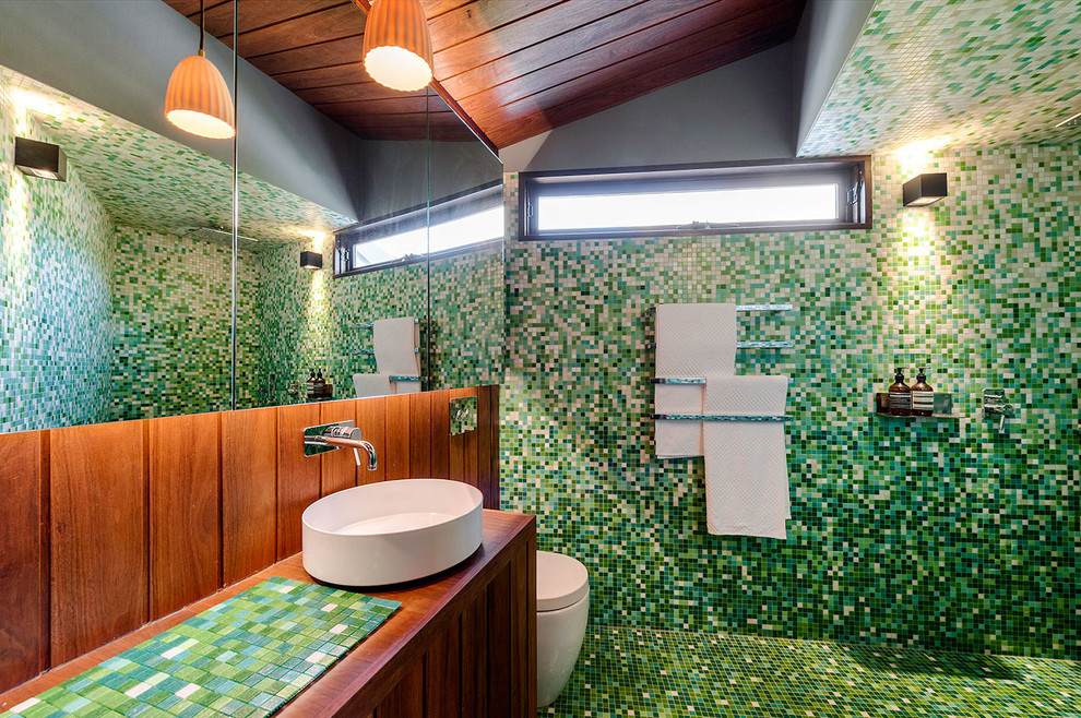 This is an example of a contemporary bathroom in Melbourne with an open shower, a one-piece toilet, green tile, mosaic tile, green walls, mosaic tile floors, a vessel sink, tile benchtops, an open shower and green benchtops.