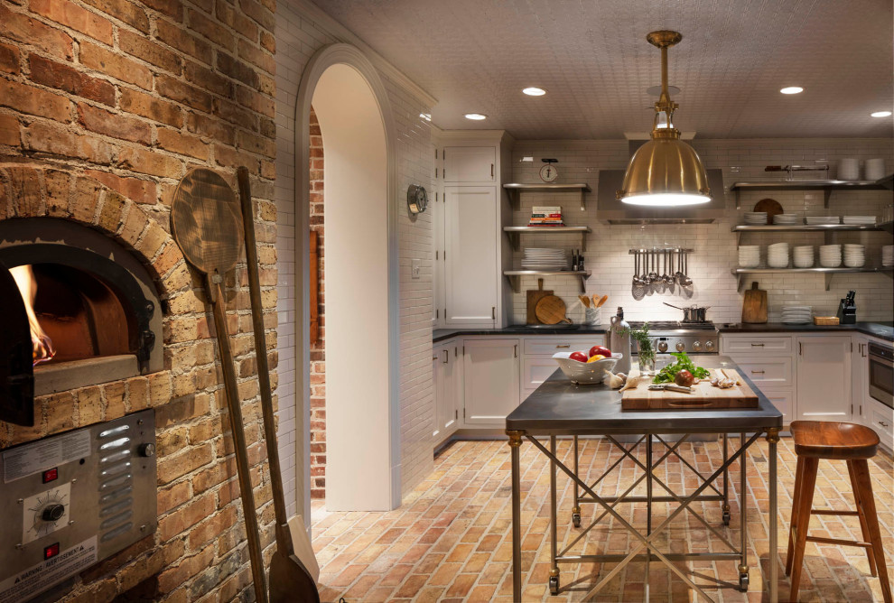 Inspiration for an expansive traditional l-shaped eat-in kitchen in Baltimore with white cabinets, zinc benchtops, white splashback, subway tile splashback, stainless steel appliances, brick floors, with island and black benchtop.