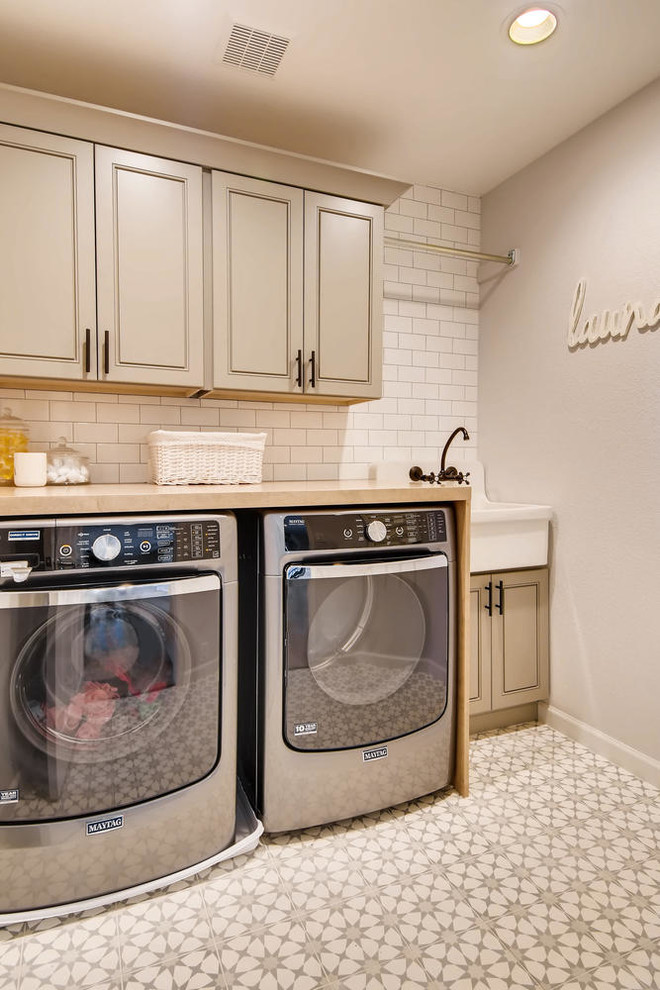 Inspiration for a large country galley dedicated laundry room in Denver with a single-bowl sink, shaker cabinets, beige cabinets, wood benchtops, white walls, ceramic floors, a side-by-side washer and dryer, multi-coloured floor and brown benchtop.