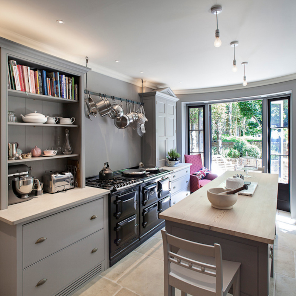 Mid-sized transitional galley limestone floor and beige floor open concept kitchen photo in Toronto with flat-panel cabinets, gray cabinets, wood countertops, black appliances and an island