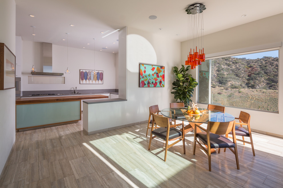 Photo of a large open plan dining in Los Angeles with white walls, limestone floors and multi-coloured floor.