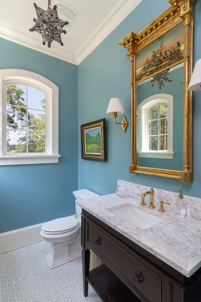 Design ideas for a traditional powder room in Charlotte with furniture-like cabinets, dark wood cabinets, a two-piece toilet, blue walls, marble floors, an undermount sink, grey floor and white benchtops.