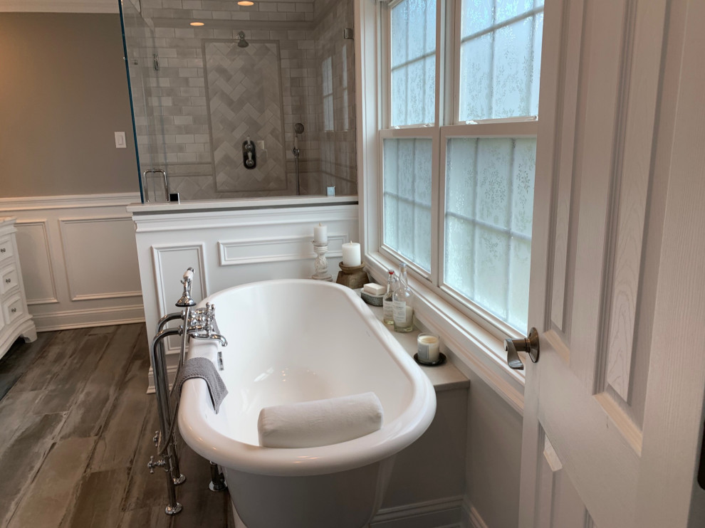 Photo of a large master bathroom in Bridgeport with raised-panel cabinets, white cabinets, a freestanding tub, a two-piece toilet, multi-coloured tile, porcelain tile, grey walls, porcelain floors, an undermount sink, marble benchtops, multi-coloured floor, a hinged shower door, multi-coloured benchtops, a double vanity, a freestanding vanity and decorative wall panelling.