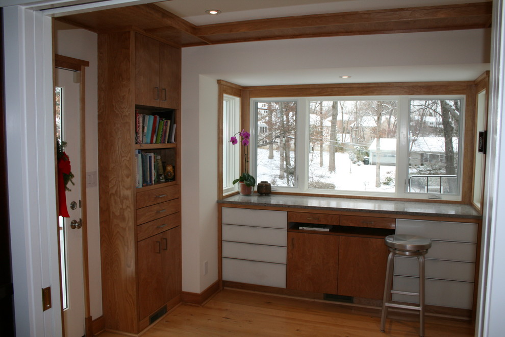 Example of a transitional u-shaped enclosed kitchen design in DC Metro with an undermount sink, flat-panel cabinets, light wood cabinets, solid surface countertops, orange backsplash, glass sheet backsplash and stainless steel appliances