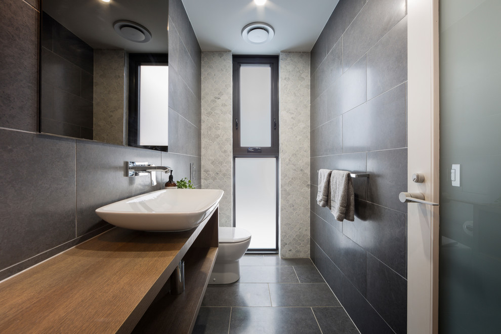 Contemporary powder room in Canberra - Queanbeyan with flat-panel cabinets, medium wood cabinets, black tile, porcelain tile, black walls, porcelain floors, wood benchtops, black floor and brown benchtops.