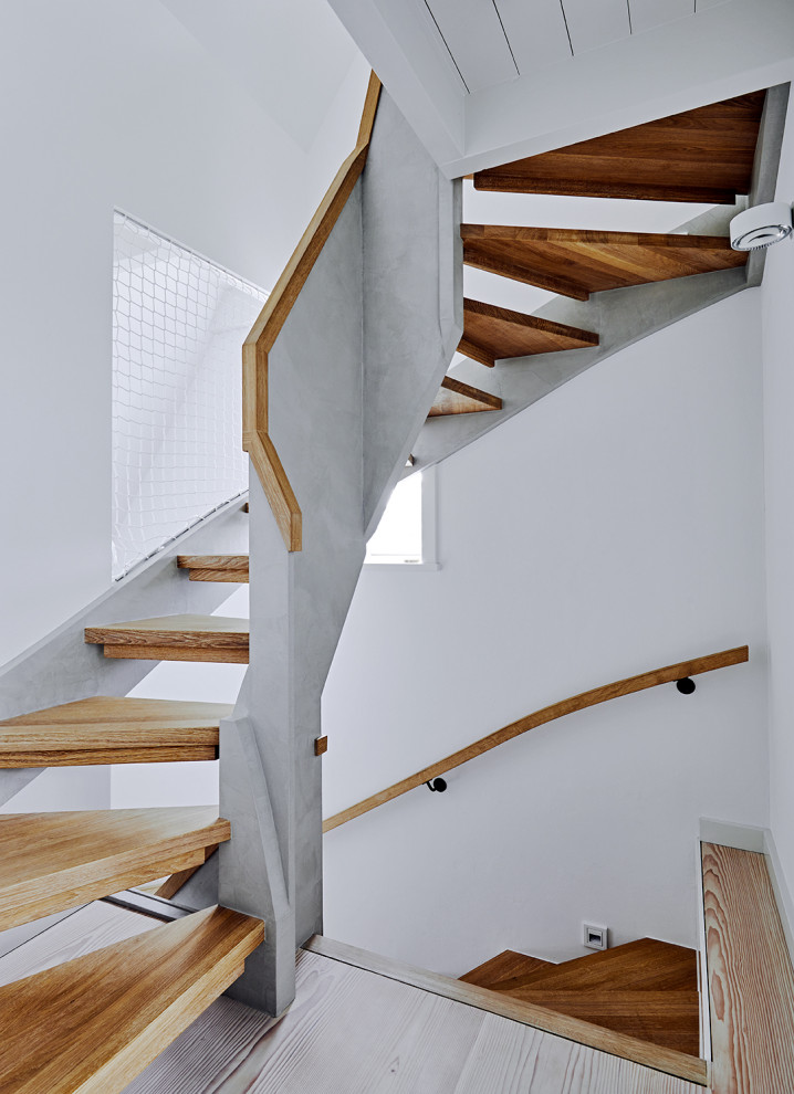 This is an example of a large contemporary wood curved staircase in Other with open risers and mixed railing.