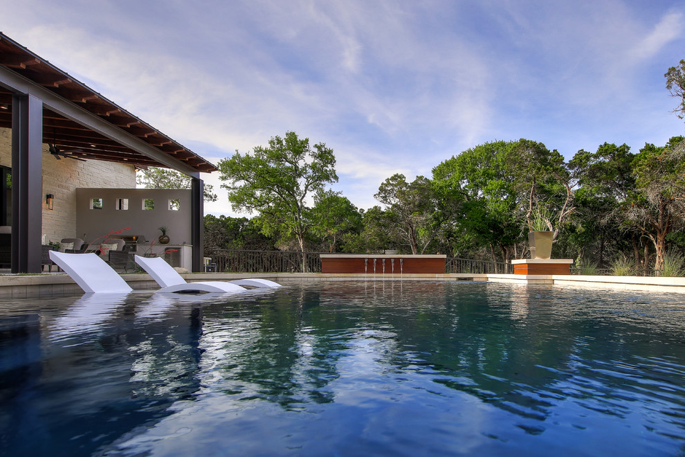 Large transitional backyard rectangular natural pool in Austin with a pool house and natural stone pavers.