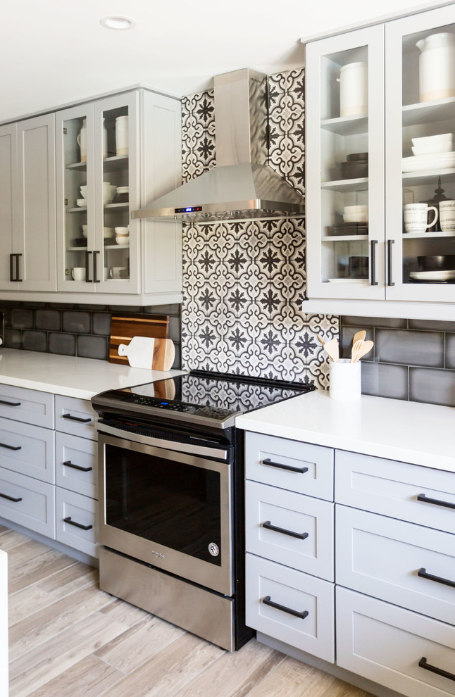 Mid-sized transitional u-shaped light wood floor and gray floor eat-in kitchen photo in Phoenix with an undermount sink, recessed-panel cabinets, gray cabinets, quartz countertops, multicolored backsplash, ceramic backsplash, stainless steel appliances, an island and white countertops