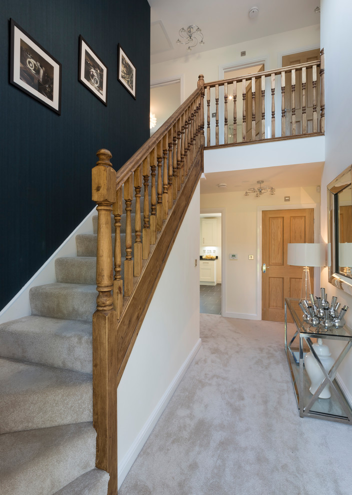 This is an example of a mid-sized transitional carpeted straight staircase in Other with carpet risers and wood railing.