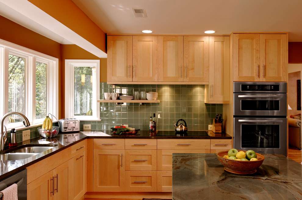 Inspiration for a mid-sized transitional l-shaped eat-in kitchen in DC Metro with an undermount sink, shaker cabinets, light wood cabinets, granite benchtops, green splashback, glass tile splashback, stainless steel appliances, light hardwood floors, with island and beige floor.
