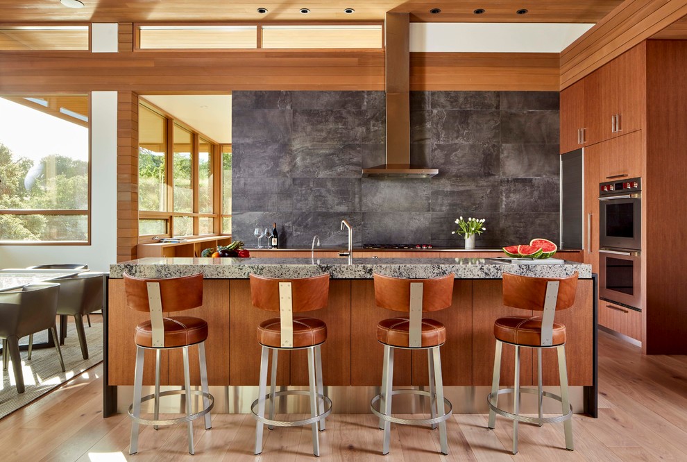 Design ideas for a midcentury eat-in kitchen in Other with flat-panel cabinets, medium wood cabinets, grey splashback, stainless steel appliances, light hardwood floors, with island, beige floor and grey benchtop.