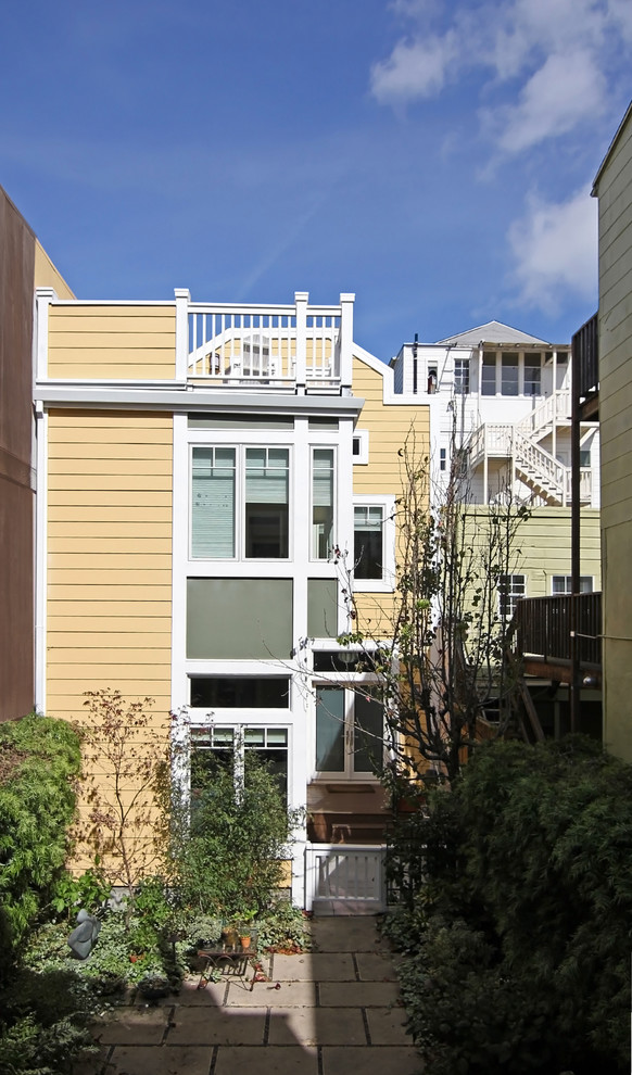 Large transitional two-storey yellow exterior in San Francisco with wood siding.