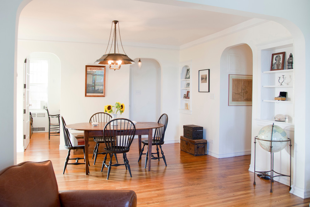 This is an example of a traditional dining room in New York with white walls and medium hardwood floors.