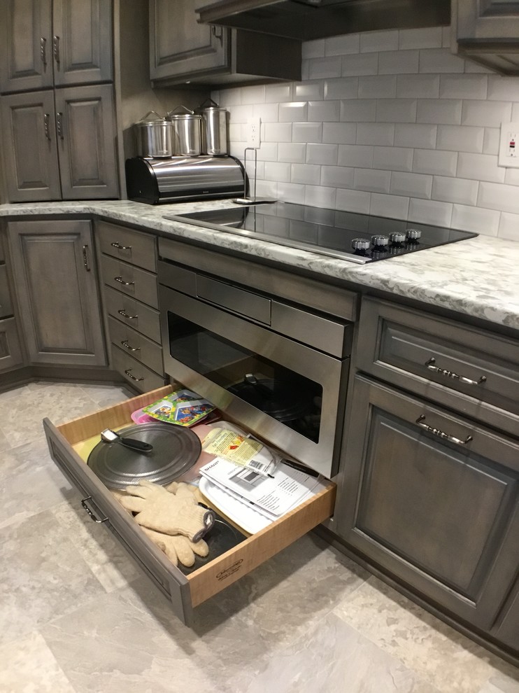 Mid-sized traditional kitchen in Cleveland with a farmhouse sink, raised-panel cabinets, grey cabinets, quartz benchtops, white splashback, subway tile splashback, stainless steel appliances, vinyl floors and multi-coloured floor.