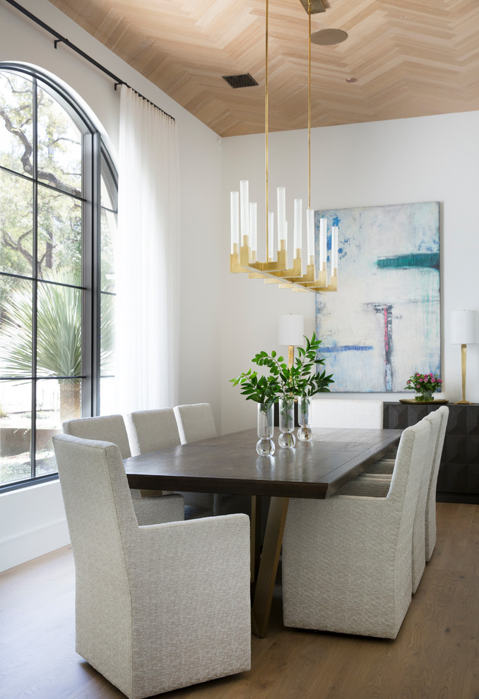 Photo of a mediterranean dining room in Austin with white walls, light hardwood floors and no fireplace.
