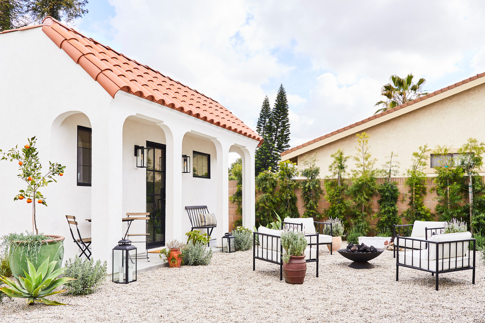 Ejemplo de fachada de casa blanca mediterránea pequeña de una planta con revestimiento de estuco, tejado plano y tejado de teja de barro