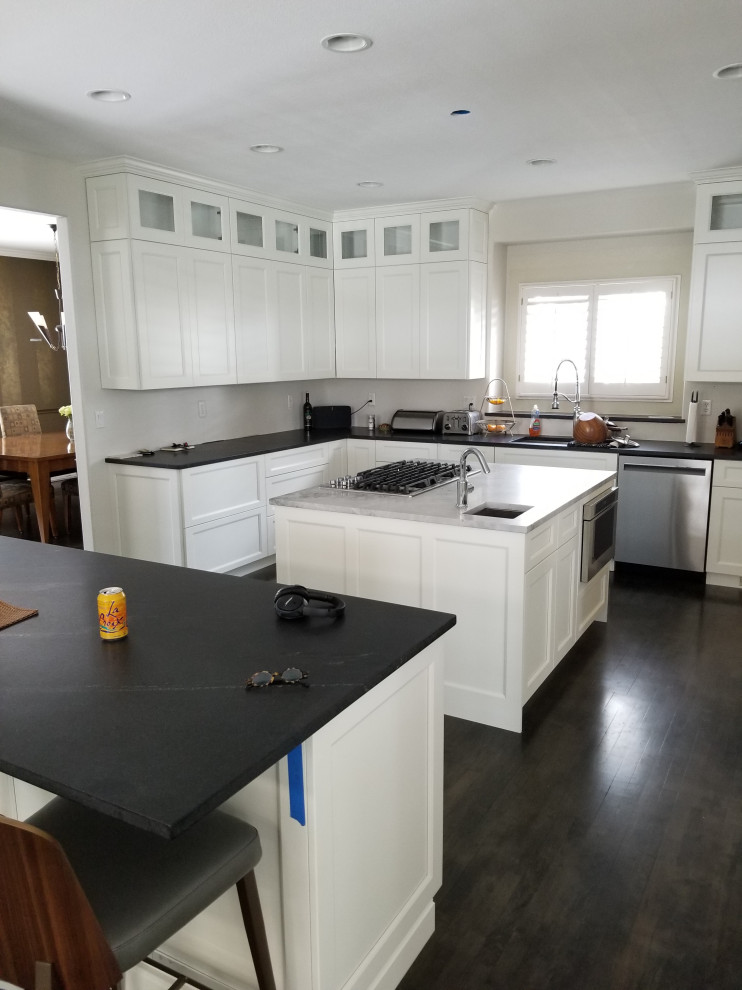 Large transitional u-shaped dark wood floor and brown floor eat-in kitchen photo in Denver with an undermount sink, shaker cabinets, white cabinets, quartz countertops, stainless steel appliances, an island and black countertops