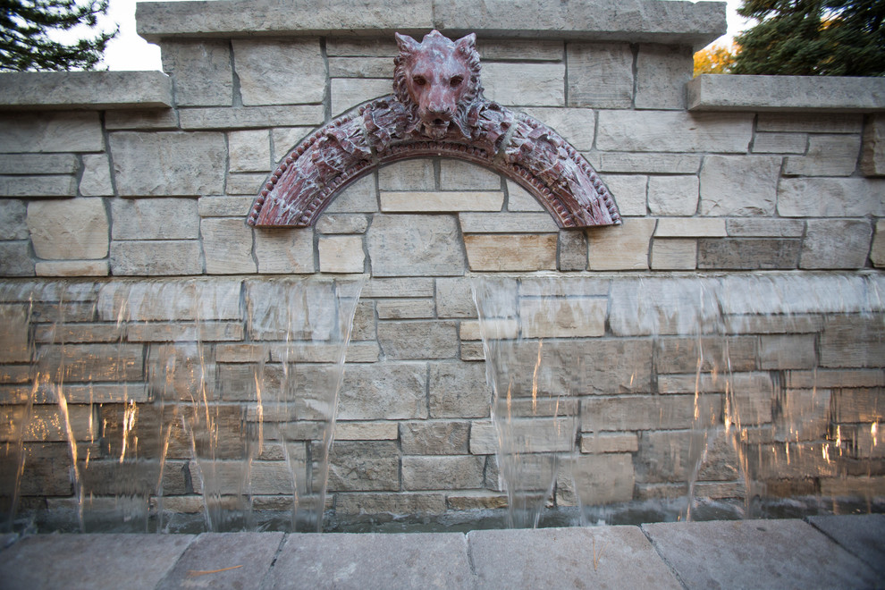 This is an example of a transitional backyard stone water fountain landscape in Omaha.
